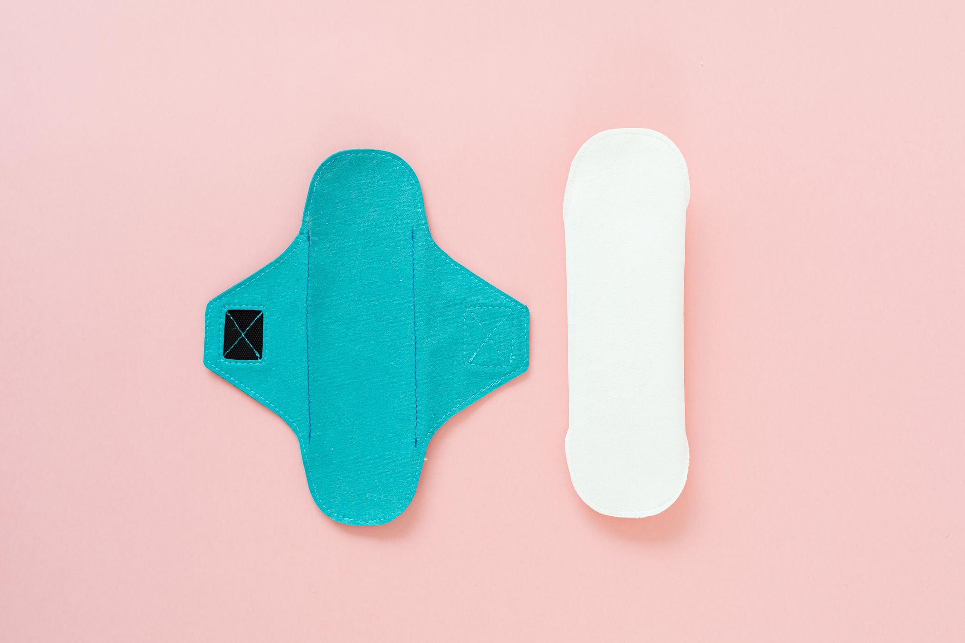 Illustration showing reusable menstrual products—cloth pads, a menstrual cup, and period underwear—for an eco‑friendly guide