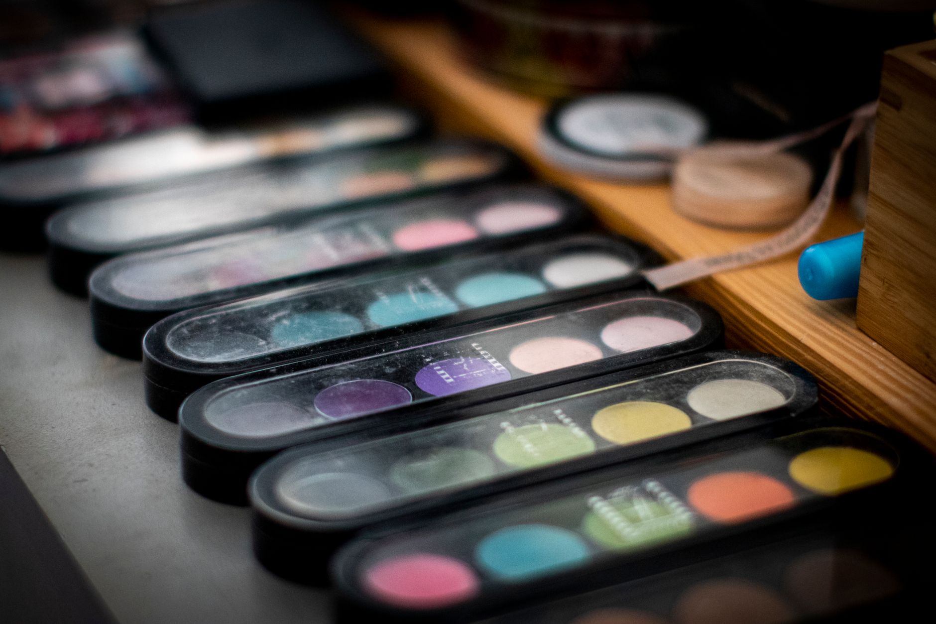 Close‑up of natural organic makeup spread on a wooden vanity, featuring eco‑friendly foundation, lipstick, and brush set.